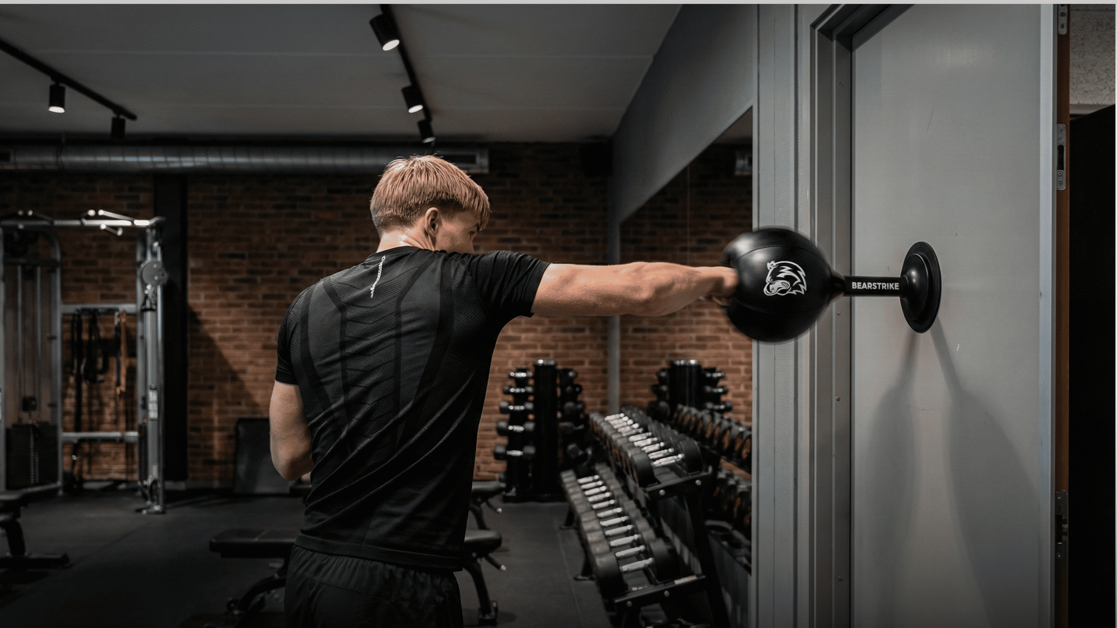 Bărbat care se antrenează în sală cu un sac de box portabil BearStrike montat pe ușă
